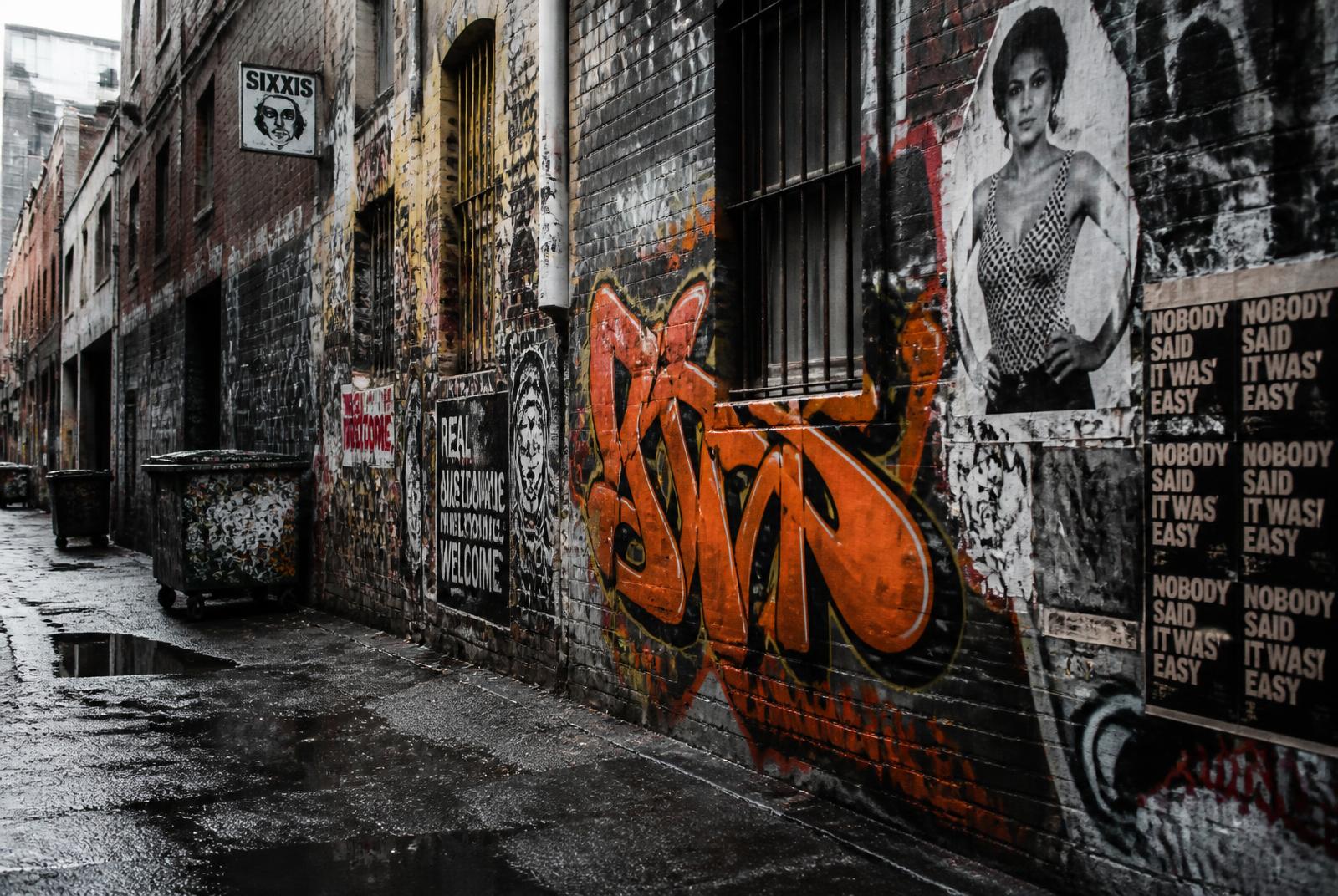 Graffiti-covered Sydney laneway with orange spray paint tag